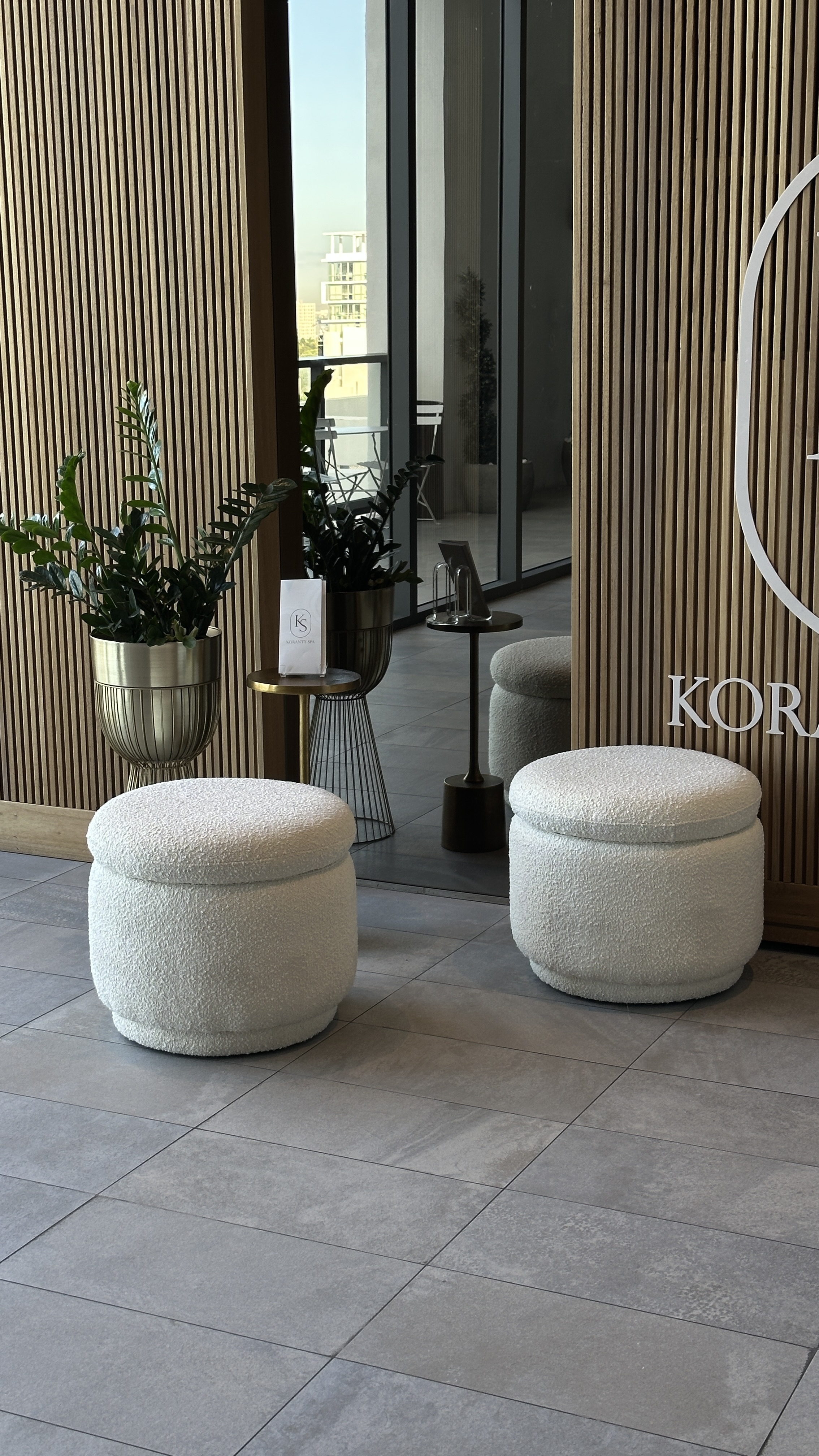 KOR hotel lobby with boucle ottomans, wood slat walls and lush tropical plants